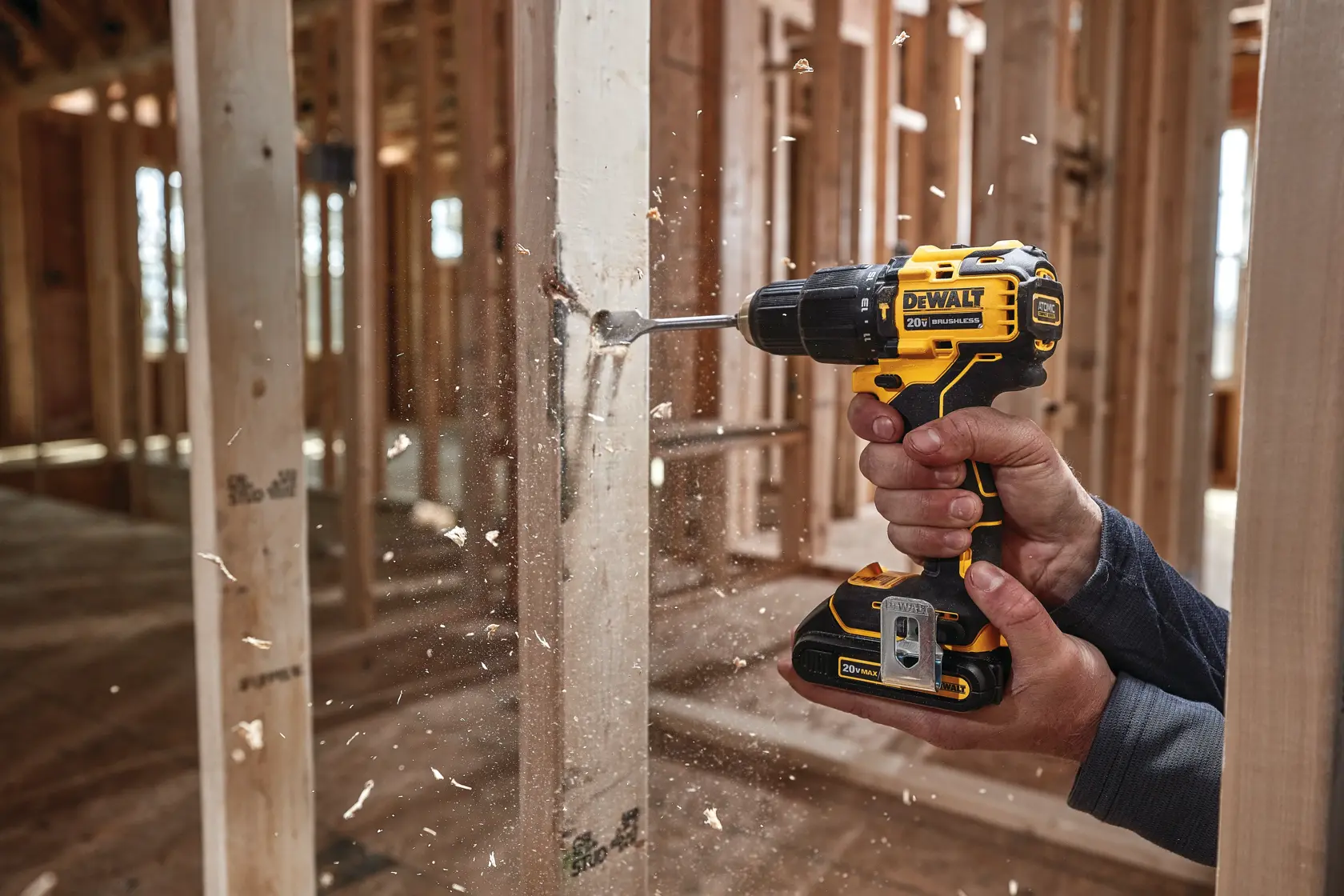 Una persona utiliza un taladro inalámbrico DEWALT para perforar una viga de madera en una obra de construcción.