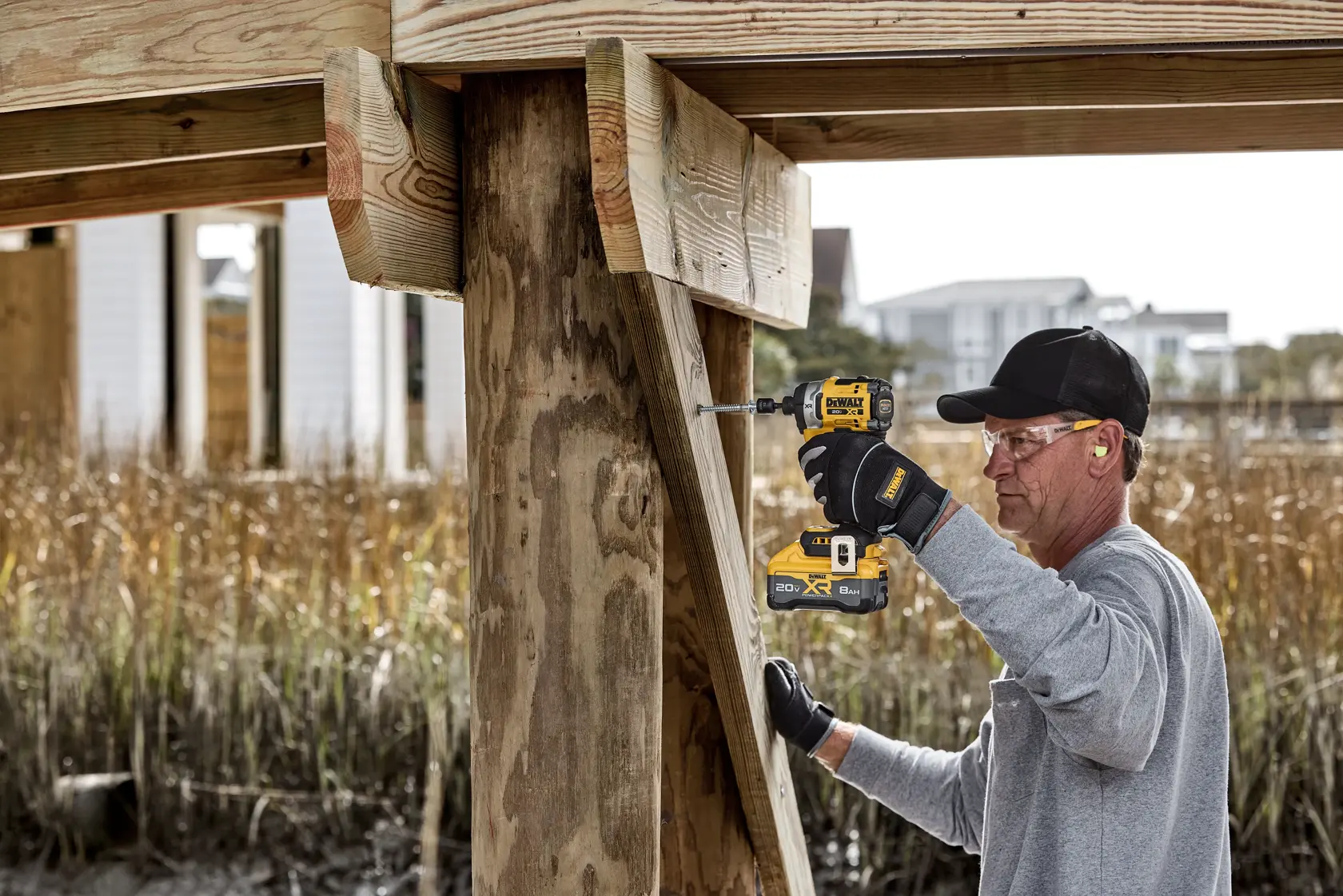 Persona usando atornillador DEWALT DCF860B para perforar madera junto a una estructura exterior.