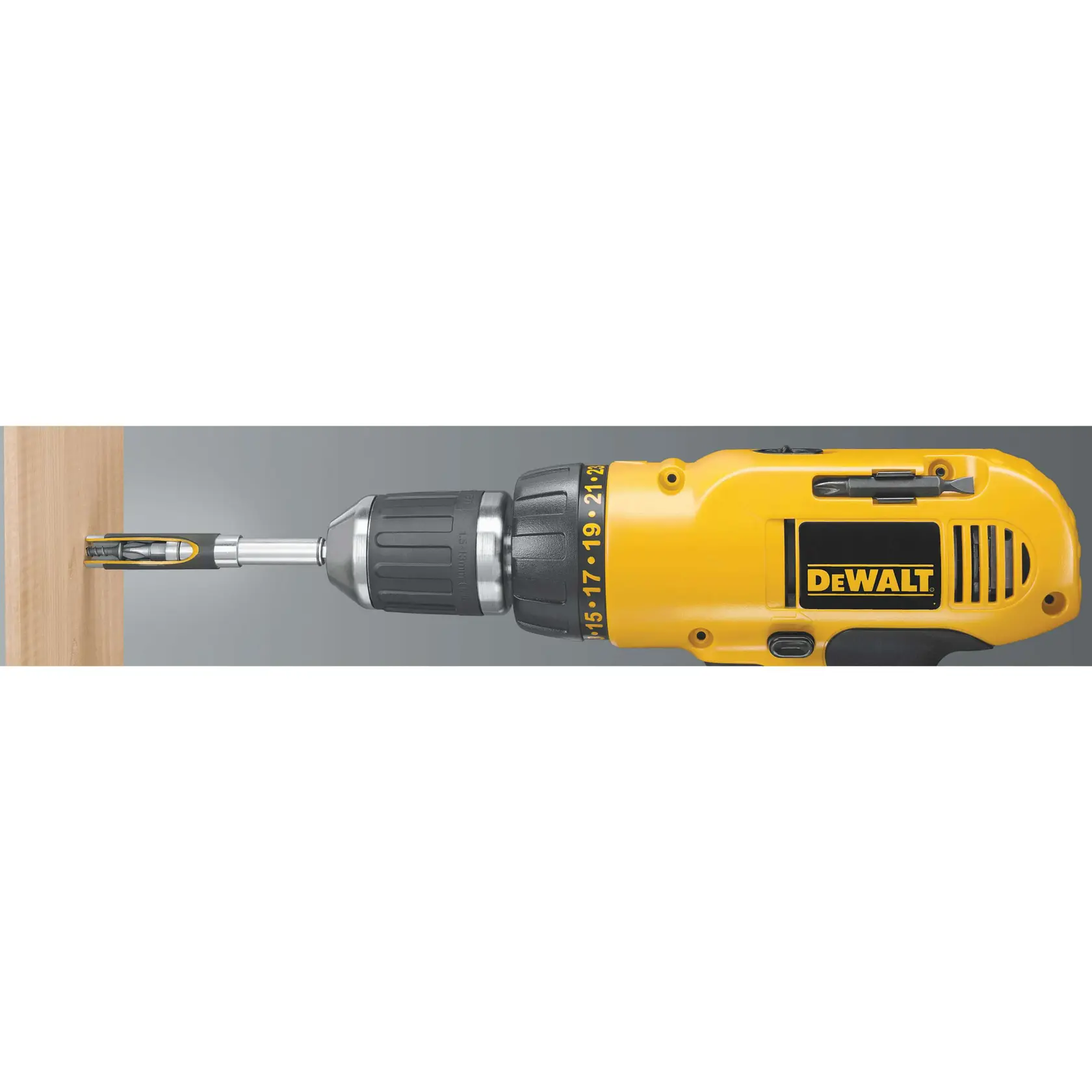 Un taladro eléctrico amarillo DEWALT se está utilizando para atornillar un tornillo en una tabla de madera. El taladro se muestra de lado, exhibiendo el logo de DEWALT y los ajustes en su cuerpo.