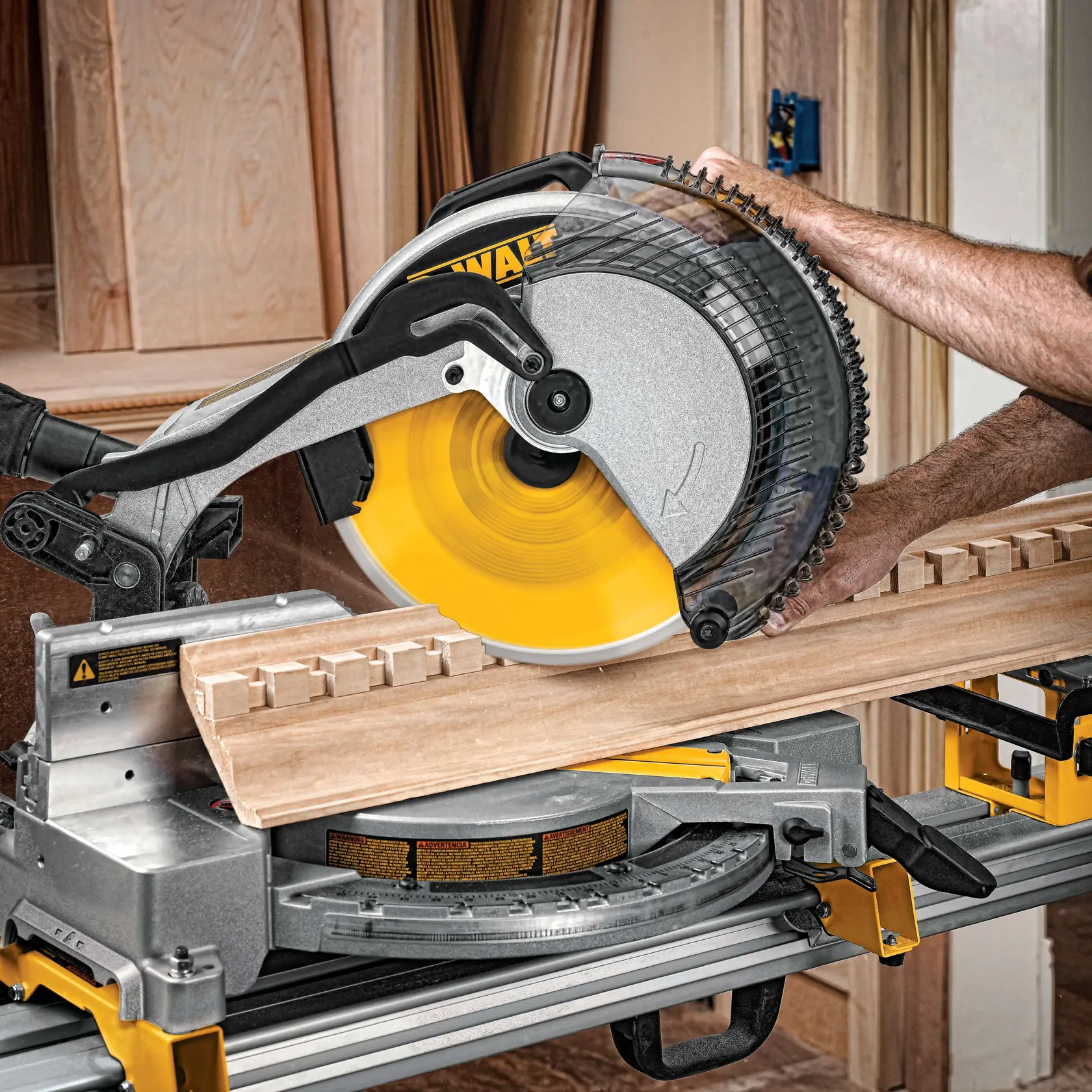 Una persona usando una sierra de inglete DEWALT para cortar una pieza de madera con ranuras, en un taller de carpintería.