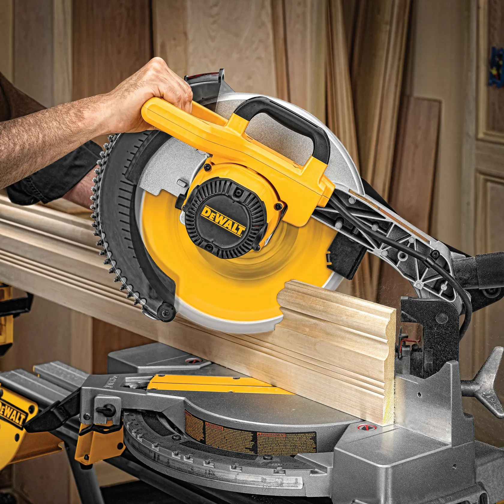Una persona está utilizando una sierra de inglete DEWALT para cortar una moldura de madera en un taller.