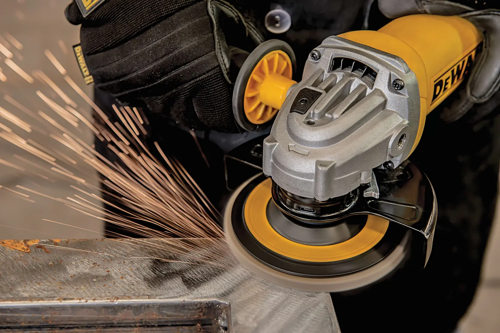 Primer plano de una persona usando una amoladora angular DEWALT para cortar o esmerilar una superficie de metal, con chispas saliendo desde el punto de contacto.